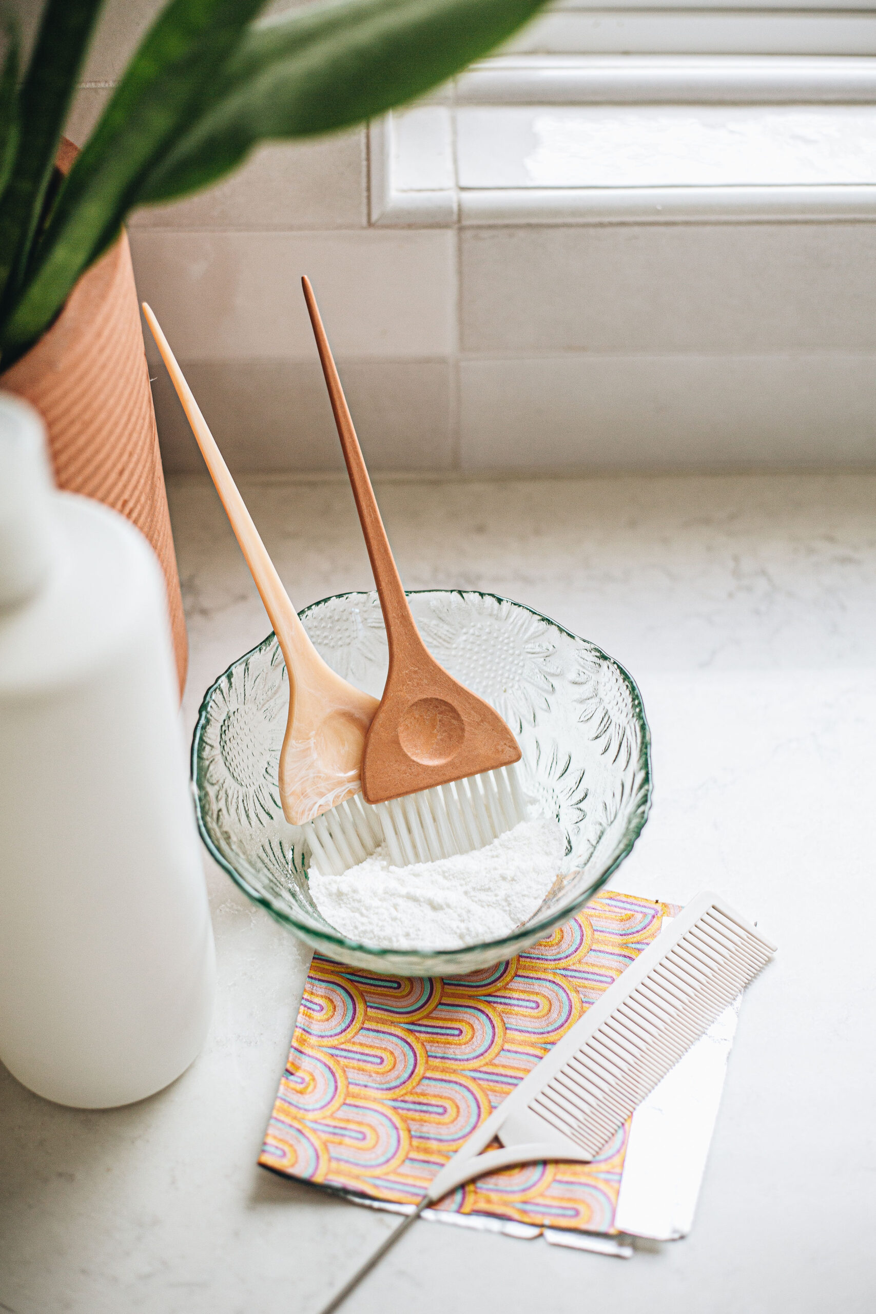 Hair color tools with lightener and brushes in a glass bowl at Ciao Bella Hair salon in Ogden